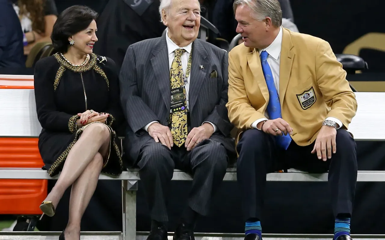 Tom Benson in a dark suit waving to fans during a Pro Football Hall of Fame ceremony