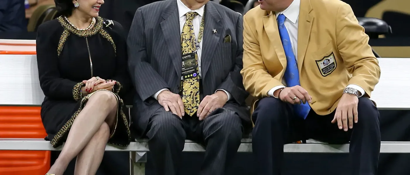 Tom Benson in a dark suit waving to fans during a Pro Football Hall of Fame ceremony